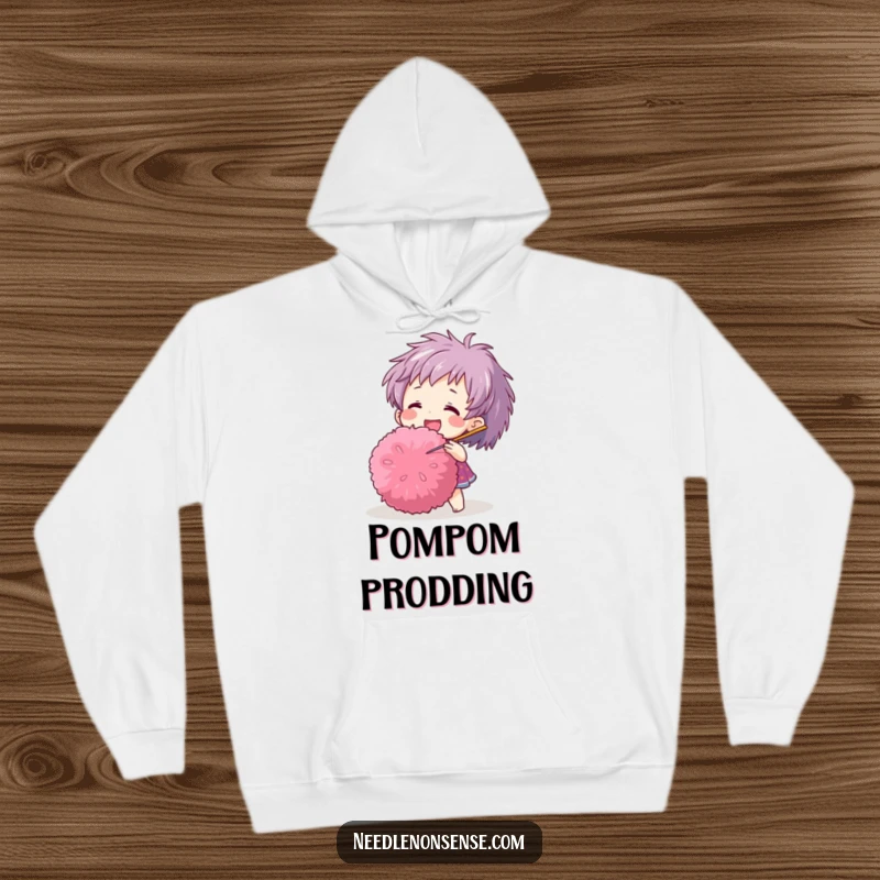 Funny hoodie with a happy character adorably poking a large pom-pom with a needle, designed for comfort and humor.