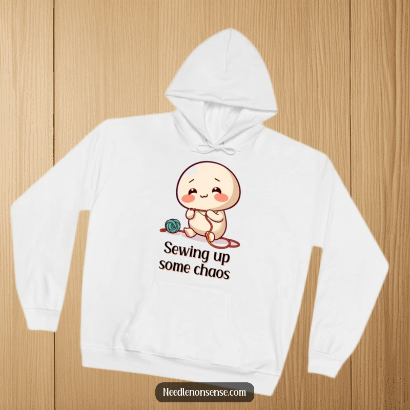 Funny hoodie with a giggling needle character energetically threading colorful string, perfect for a cozy and amusing wear.