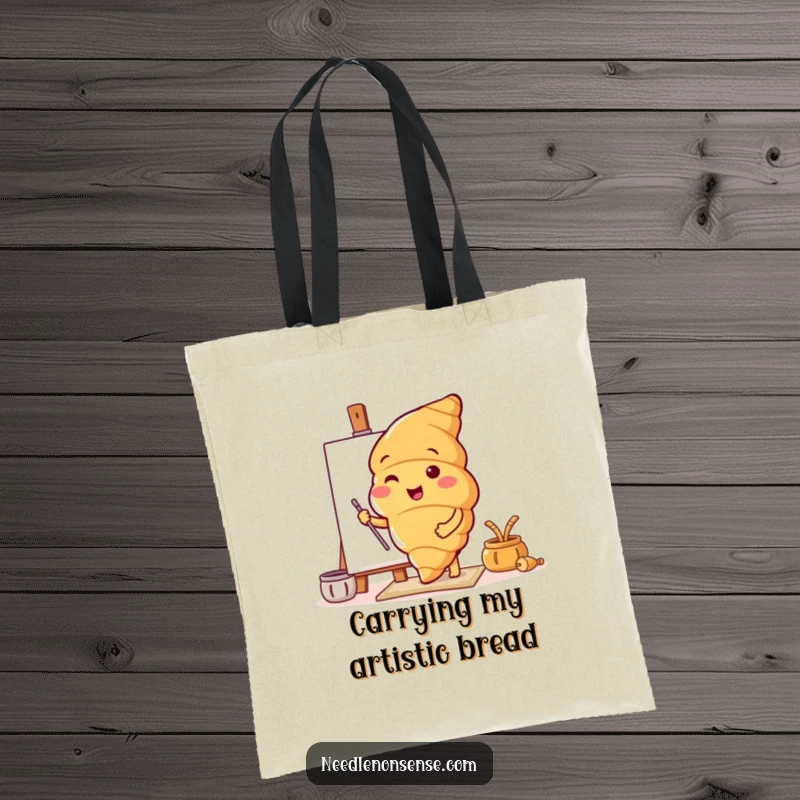 Funny tote bag featuring a croissant character setting up a canvas, ideal for artists carrying supplies.